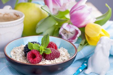 Bir tabak yulaf ezmesi taze ahududu ve nane. Aromalı kahve. Bir buket bahar lale. Paskalya tavşanı.