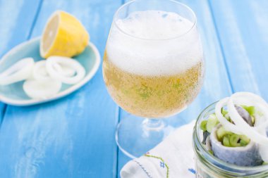 Geleneksel Hollanda limon ve bir kavanoz içinde soğan ile ringa balığı Marine. Bir bardak taze Belçika birası. Mavi bir arka plan üzerinde deniz ürünleri. Kopya sapce