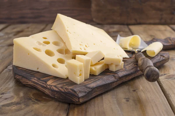 Peynir ile büyük ve küçük delikler. Ahşap tahta ve bıçak. Geleneksel Hollanda peynir. Kopya alanı. — Stok fotoğraf
