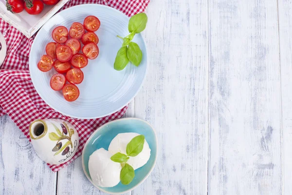 Traditioneller italienischer Salat mit frischen Kirschtomaten und weichem Mazarella-Käse mit Basilikum und Olivenöl. Zutaten für Salat. Portionen in Tellern. Freiraum für Text — Stockfoto