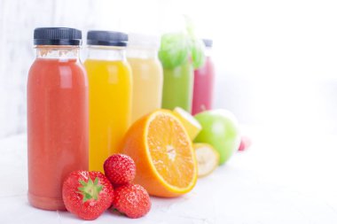 Birçok farklı meyve ve çilek ve suları, plastik şişe. Karpuz, muz, applcsin, yaban mersini, çilek, beyaz bir arka plan üzerinde fesleğen. Vitamin ve sağlıklı gıda. Detoks. Kopya alanı