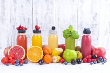 Birçok farklı meyve ve çilek ve suları, plastik şişe. Karpuz, muz, applcsin, yaban mersini, çilek, beyaz bir arka plan üzerinde fesleğen. Vitamin ve sağlıklı gıda. Detoks. Kopya alanı