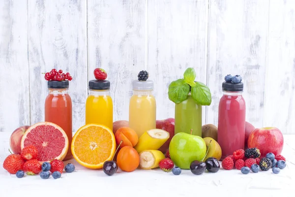 Många olika frukter och bär och juice i plastflaskor. Vattenmelon, banan, applcsin, blåbär, jordgubbar, basilika på en vit bakgrund. Vitamin och hälsosam mat. Detox. Kopiera utrymme — Stockfoto
