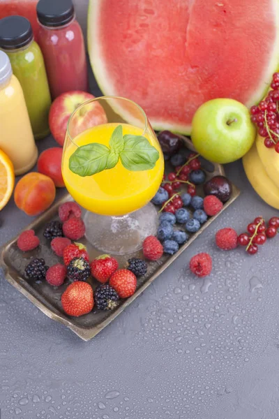 Şişeler, farklı ve bir bardak meyve suyu. Çeşitli meyveler ve meyve. Gri arka plan. Gıda detoks. Kopya alanı