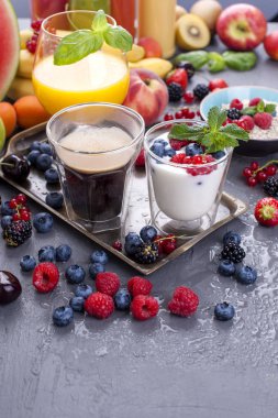 Farklı meyveler ve meyve üzerinde gri bir arka plan, taze sıkılmış meyve suyu, kahve, yoğurt ve kahvaltı için çilek. Vitamin ve detoks gıda. Kopya alanı