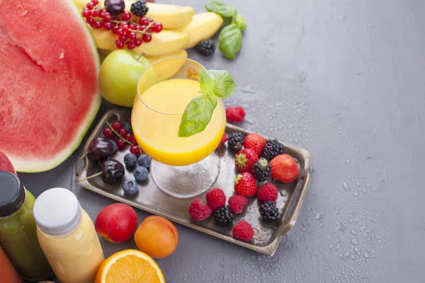 Farklı meyveler ve meyve üzerinde gri bir arka plan, taze sıkılmış meyve suyu. Vitamin ve detoks gıda. Kopya alanı