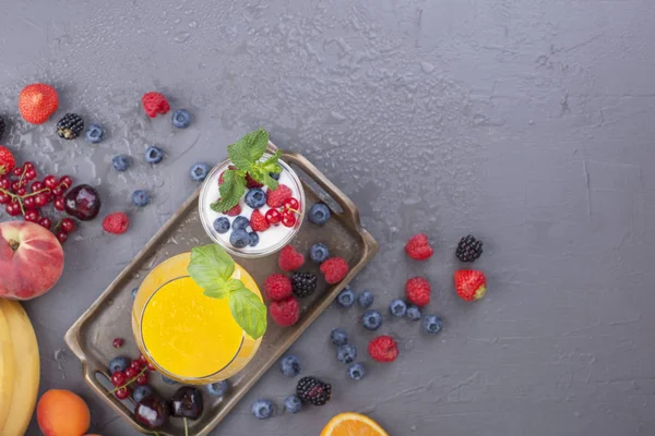 Farklı meyveler ve meyve bir gri arka plan, taze meyve, yoğurt ve kahvaltı için çilek suyu. Vitamin ve detoks gıda. Kopya alanı