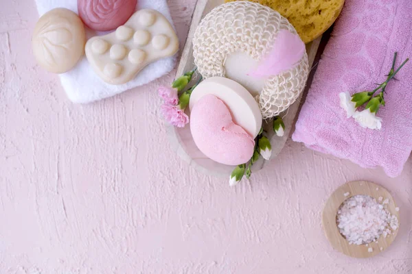 Spa ve banyo aksesuarları. Fotoğraf pembe renklerde. Canlı çiçekler ve sabun. Sakin ol. Uzay kopyalayın. Düz yatıyordu