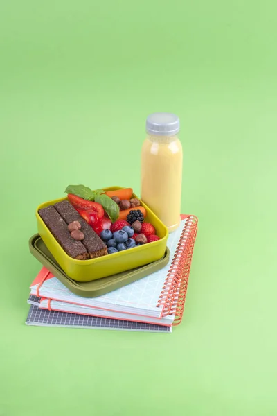 De doos van de lunch met gezonde voeding en SAP van verse bessen. Toast en apple. boeken voor school en groene achtergrond. afhaalmaaltijden voedsel. kopie ruimte. — Stockfoto