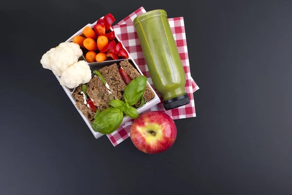 School lunch in a plastic container. Juice from fresh berries and toast with vegetables for a healthy lunch. Black background and free space for text. Lunch at the office. Copy space