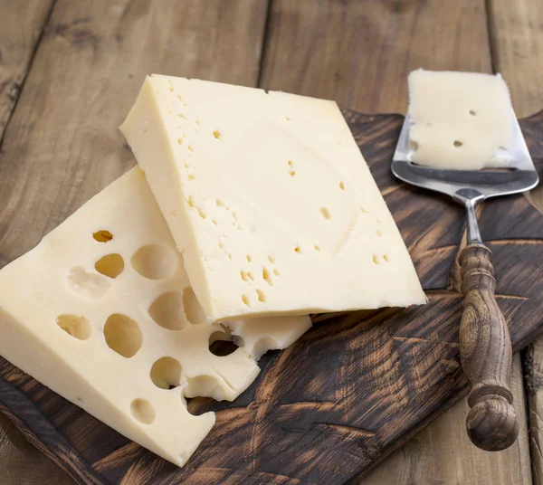 Um belo queijo suíço com buracos, um produto lácteo útil. Comida saborosa. Foto de estilo country. Lugar para SMS. Espaço de cópia — Fotografia de Stock