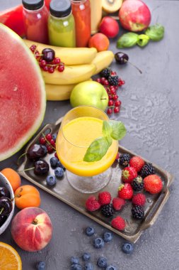 Birçok farklı meyve ve çilek, suyu şişelerde. Vitamin ve sağlıklı gıda. Yaz ürünleri ve bir bardak portakal suyu. Kopya alanı