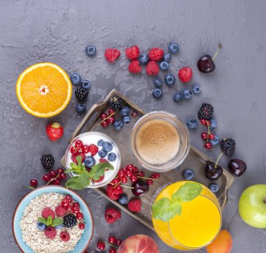 Birçok farklı meyve ve çilek. Vitamin ve sağlıklı gıda. Portakal suyu bir bardak, yoğurt, müsli çilek ve güzel kokulu sabah kahve ile. Lezzetli kahvaltı. Kopya alanı