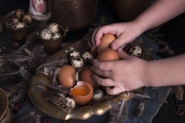 Çocuk eller çerçeve, Paskalya yumurtaları irili ufaklı, tüyler. Vintage tarzı fotoğrafta. Kırsal aksesuarları. Kopya alanı
