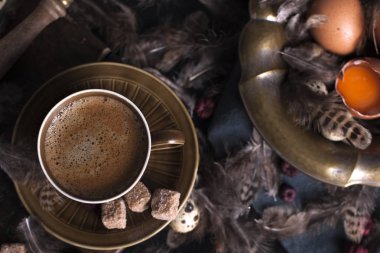 Bir fincan hoş kokulu kahve ve kahverengi şeker. Vintage Fotoğraf. Yumurta tavuk ve bıldırcın ve tüy. Paskalya. Fotoğraf bir rustik tarzda. Kopya alanı