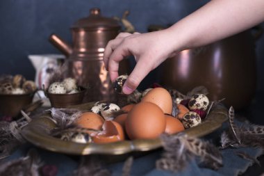 Çocuk eller çerçeve, Paskalya yumurtaları irili ufaklı, tüyler. Vintage tarzı fotoğrafta. Kırsal aksesuarları. Kopya alanı.