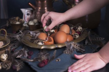 Çocuk eller çerçeve, Paskalya yumurtaları irili ufaklı, tüyler. Vintage tarzı fotoğrafta. Kırsal aksesuarları. Kopya alanı