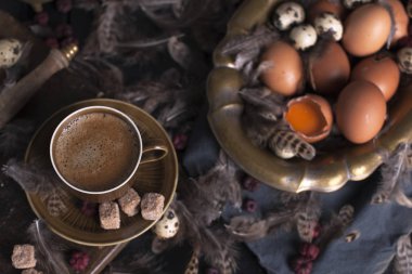Bir fincan hoş kokulu kahve ve kahverengi şeker. Vintage Fotoğraf. Yumurta tavuk ve bıldırcın ve tüy. Paskalya. Fotoğraf bir rustik tarzda. Kopya alanı
