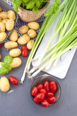 Taze yeşil soğan, Genç patates, domates ve Yeşil fesleğen. Sağlıklı gıda ve vitamin. Yaz mevsim sebzeleri. Kopya alanı