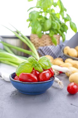 Taze yeşil soğan, Genç patates, domates ve Yeşil fesleğen. Sağlıklı gıda ve vitamin. Yaz mevsim sebzeleri. Kopya alanı