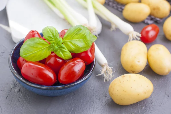 Taze yeşil soğan, Genç patates, domates ve Yeşil fesleğen. Sağlıklı gıda ve vitamin. Yaz mevsim sebzeleri. Kopya alanı