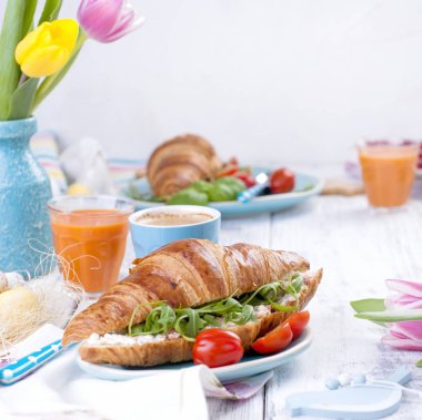 Beyaz bir arka plan üzerinde lezzetli bahar kahvaltı. Taze lale buketi. Küçük ve büyük renkli Paskalya yumurtaları. Yulaf ezmesi, kahve, taze çilek.