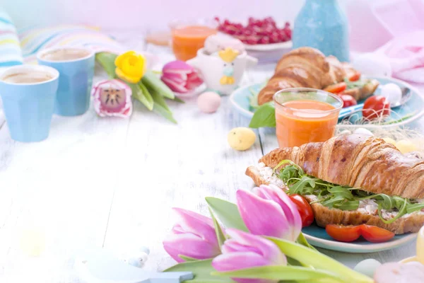 Paskalya kahvaltı. Kruvasan roket salata, peynir ve aromatik kahve ile bir aile kahvaltı. Taze lale pembe renkli ve farklı renklerde yumurta. Metin için özgür yer. Bahar için dekorasyon