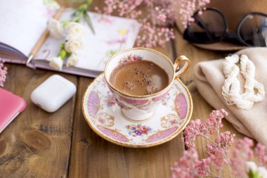 Sabah rahat bir kafede kahve. Not defteri günde planlama. Pembe çiçek dekor. Metin için özgür yer. Kartı kopya alanı