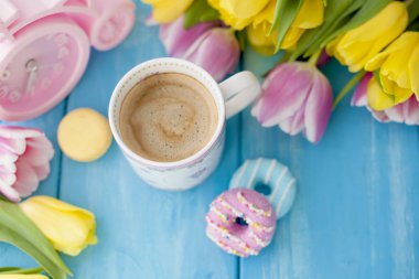 Bahar sabah, hoş kokulu kahve ve lale sarı ve pembe renk. Donuttsy kopyalar. Mavi ahşap arka plan, metin ve posta kartı için bir yer.