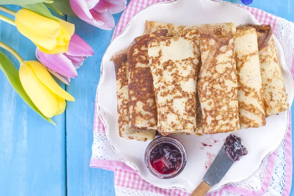Ev yapımı reçel bahar karnaval için geleneksel krep. Rus kahvaltı. Lale parlak çiçekler. Mavi arka plan. Metin veya bir kartpostal için boş alan.