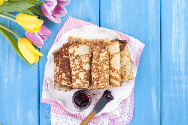 Ev yapımı reçel bahar karnaval için geleneksel krep. Rus kahvaltı. Lale parlak çiçekler. Mavi arka plan. Metin veya bir kartpostal için boş alan.