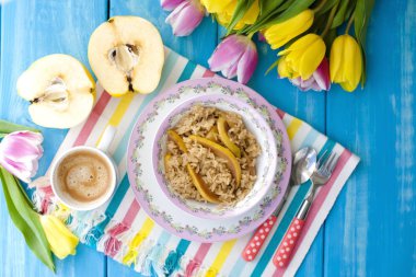 Meyve ve aromatik sabah kahve kahvaltı için yulaf ezmesi. Mavi arka plan ve laleler... Kopya alanı