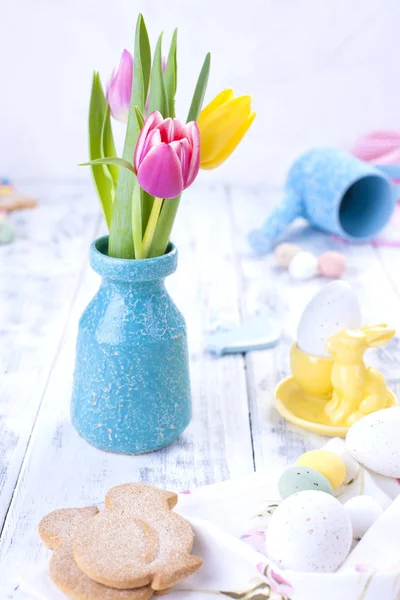 A bouquet of spring tulips for Easter. On white wooden steel. Easter decor and eggs of different colors. Free space for text or a postcard. — Stock Photo, Image