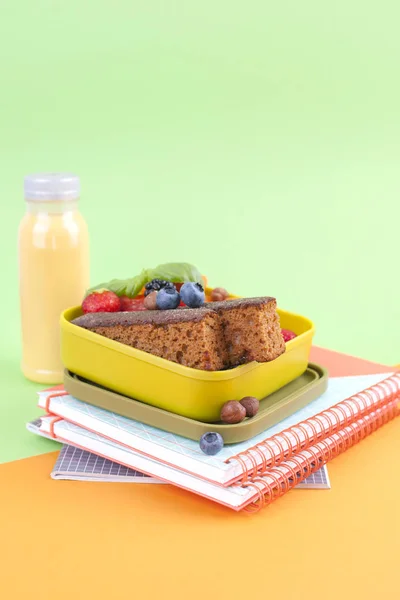 Almuerzo escolar en una caja y jugo con fruta sobre fondo verde y un libro. Espacio libre para texto. Copiar espacio —  Fotos de Stock