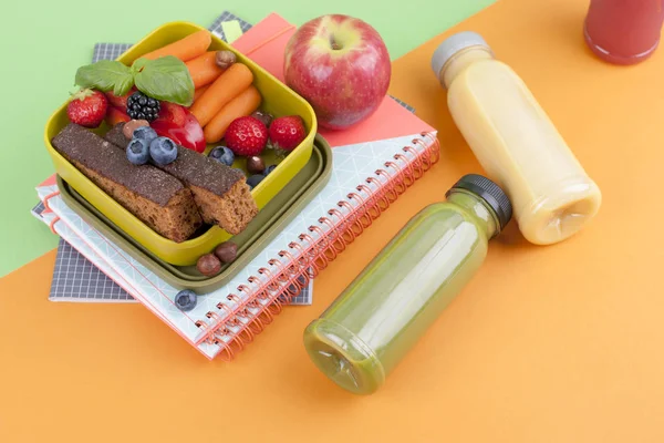 Almuerzo escolar en una caja y jugo con fruta sobre fondo verde y un libro. Espacio libre para texto. Copiar espacio —  Fotos de Stock