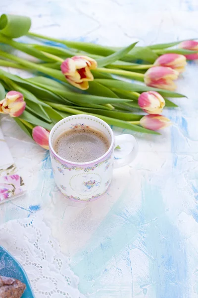 Una taza de café y un ramo de flores frescas de primavera. Tulipanes. Fondo brillante con pinturas azules. Espacio libre para texto o postal — Foto de Stock