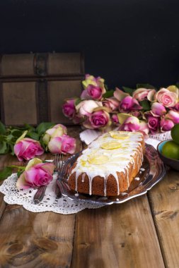 Eski bir tepsi, pembe gül ve ahşap arka plan kireç ve beyaz kremalı Cupcake