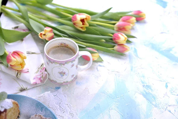 Aromatische koffie in de ochtend, boeket tulpen met gekleurde bloemblaadjes. Op witte met een blauwe achtergrond. Vrije ruimte voor tekst of een briefkaart. — Stockfoto