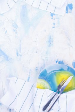 Beyaz masa ile mavi renkli. Mavi çizgili beyaz bir havlu. Güzel bir tabak çatal ve bıçak. Metin, kartpostal veya reklam için boş alan.