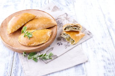 Peynir ve Yeşiller kahvaltı için taze ev yapımı börek. Porsiyon börek. Ahşap plaka ve beyaz bir arka plan. Metin veya reklam için boş alan