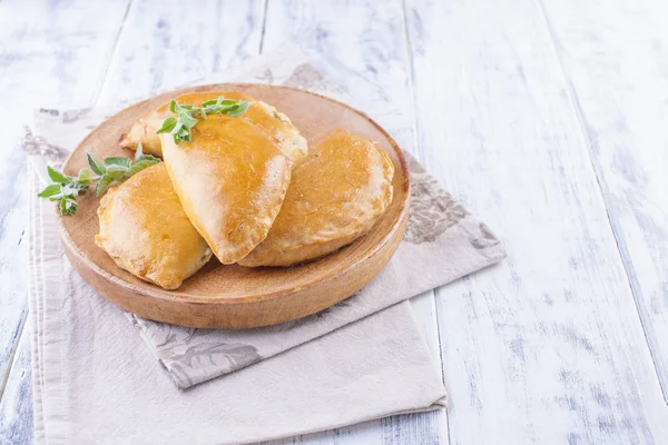 Fresh homemade pies for breakfast. Portion pies. On a wooden plate and on a white background. Free space for text or advertising — Stock Photo, Image