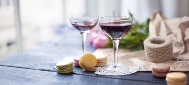 İki bardak kırmızı şarap. Kahverengi kağıt pembe gül buketi. Renk pasta makarna. Pencerenin. Metin veya kartpostal için boş alan