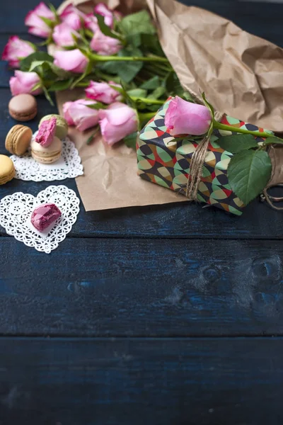 Un bouquet de roses roses, une boîte avec un cadeau. Macarons de pâtes sucrées de différentes couleurs, le jour de la Saint-Valentin — Photo