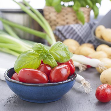 Genç patates, küçük kiraz domates, yeşil soğan ve yemek için fesleğen. Sağlıklı beslenme için sebze. Kopya alanı