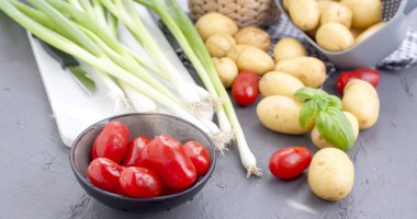Genç patates, küçük kiraz domates, yeşil soğan ve yemek için fesleğen. Sağlıklı beslenme için sebze. Kopya alanı