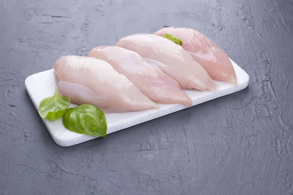 Chicken fillet on a marble plaque. Gray background and meat. Preparation of dinner. Copy space