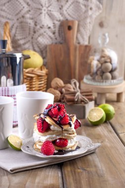 Beyaz krem ve taze kırmızı ahududu meyveleri ile tatlı ev punkcakes. İki bardak çay için kahvaltı ve bir su ısıtıcısı. ahşap bir arka plan üzerinde. metin veya reklam için boş alan.