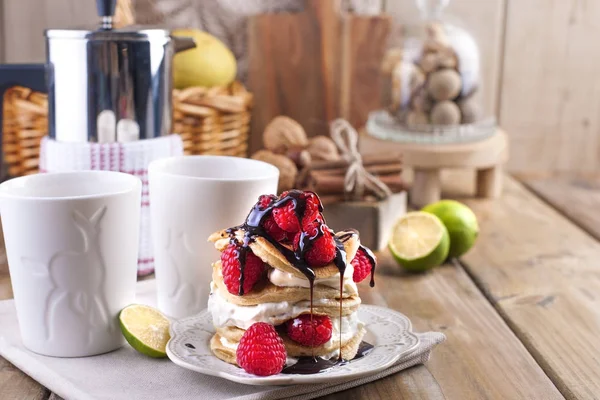 Gâteaux maison sucrés avec crème blanche et framboises rouges fraîches. Deux verres de thé pour le petit déjeuner et une bouilloire. sur un fond en bois. espace libre pour le texte ou la publicité . — Photo