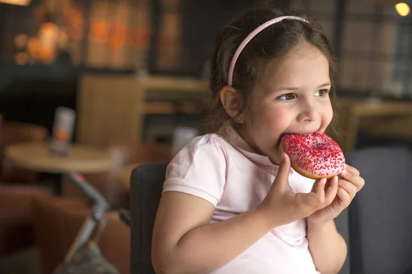 Glückliches Mädchen, das in einem Café Gebäck isst. schädliche süße Nahrung. Trends bei Lebensmitteln. Kopierraum — Stockfoto