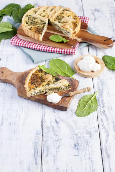 Torta fatta in casa con spinaci e formaggio, su uno sfondo di legno bianco. porzione di torta — Foto Stock